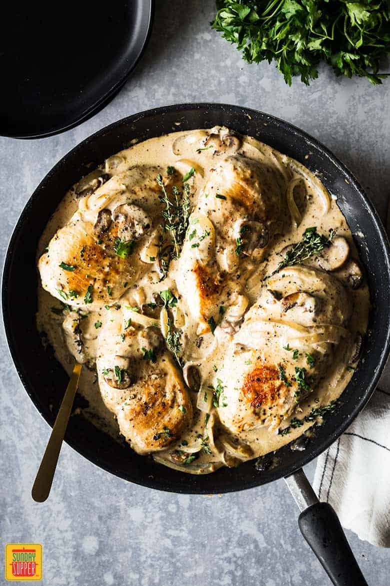 Chicken breast and mushroom recipe in pan with fresh thyme and parsley, ready to serve