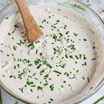 How to make blue cheese dressing: blue cheese dressing in a glass bowl with a wooden spoon