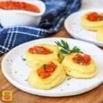 Marquis potatoes on a white plate with fresh tomato topping