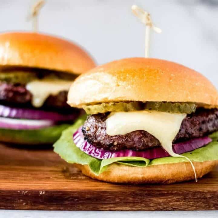 two bison burgers on a wooden cutting board