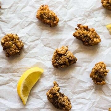 Pan Fried Oysters on a white paper with lemon wedges