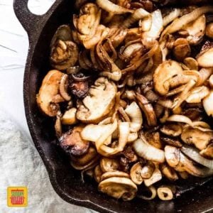 Sauteed Mushrooms and Onions in a black skillet, caramelized and ready to serve