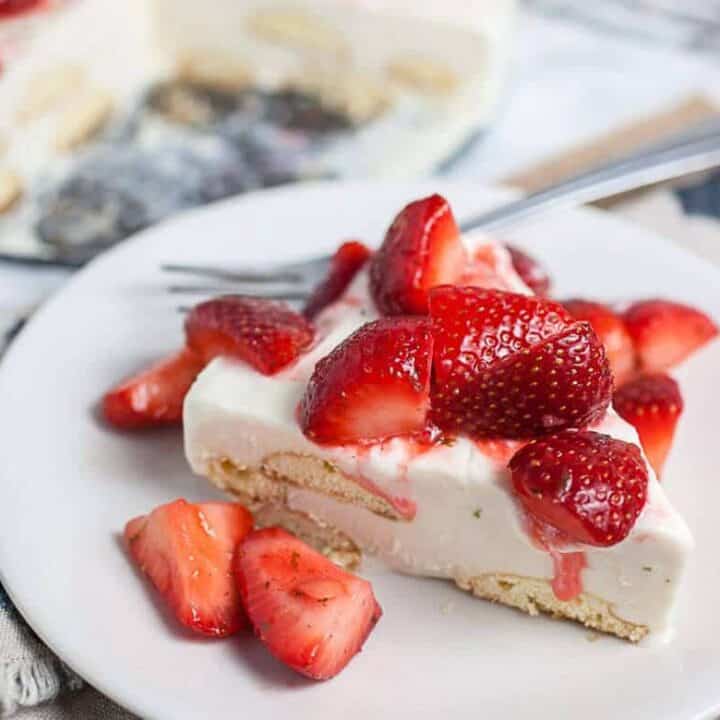 Single slice of Carlota de Limon on a white plate with fresh strawberries
