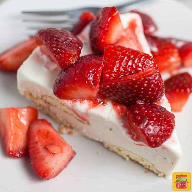 Single slice of Carlota de Limon with fresh strawberries and a fork to serve