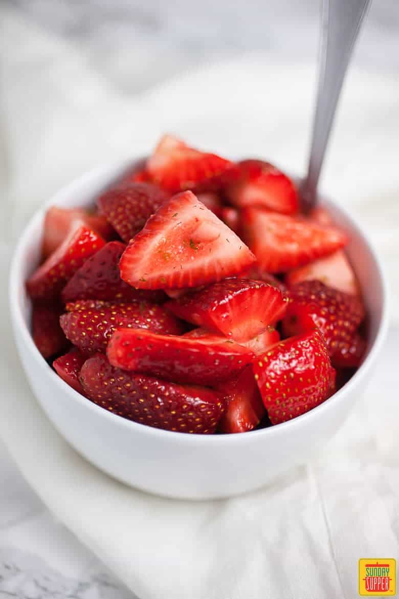 Sliced strawberry lime topping in a little white cup for Carlota de Limón