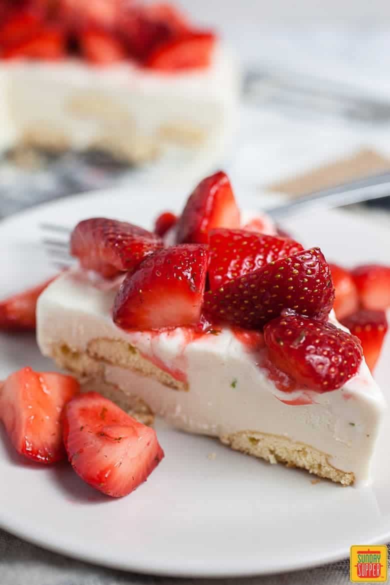 Single slice of Carlota de Limon with strawberries on top on a white plate