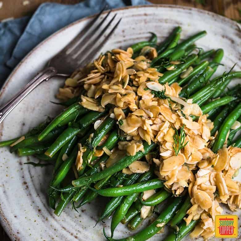 Green beans almondine on a grey speckled plate with a fork