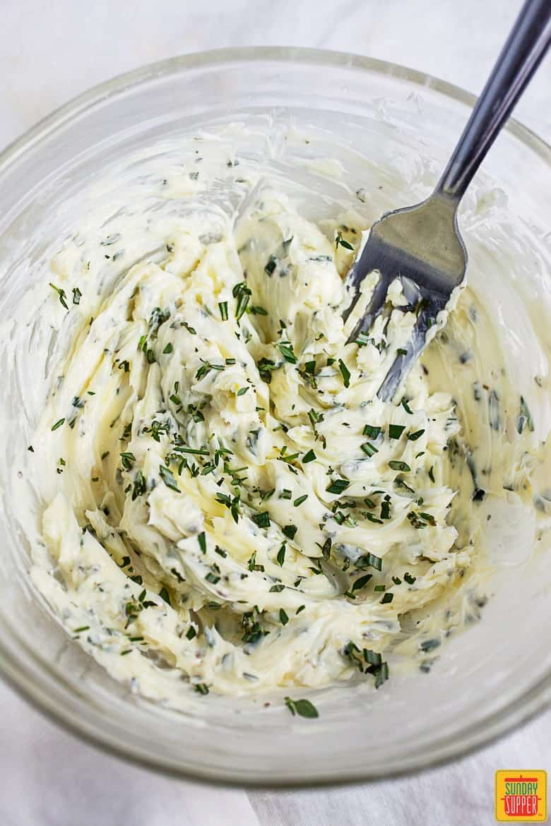 Compound butter mixed in a glass bowl with a fork in it