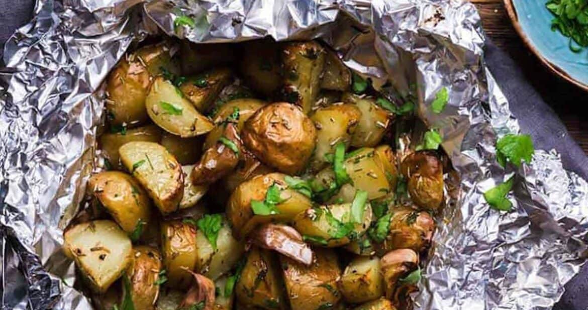 Potatoes in foil with garlic and herbs on a wooden surface