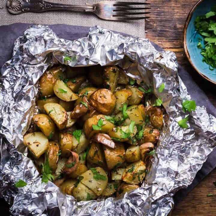 Potatoes in foil with garlic and herbs on a wooden surface