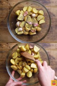 Mixing cut potatoes with olive oil and seasonings in a glass bowl