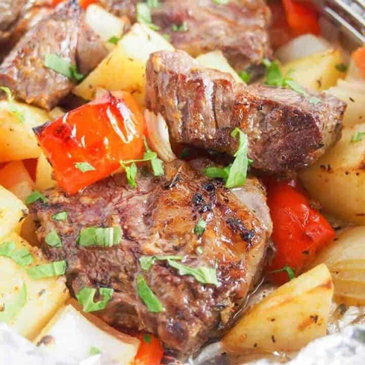 Close up of steak foil packs with potatoes, peppers, and onions, cooked and ready to eat