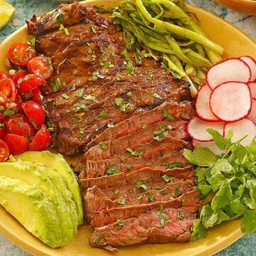carne asada sliced on a plate with vegetables and avocado