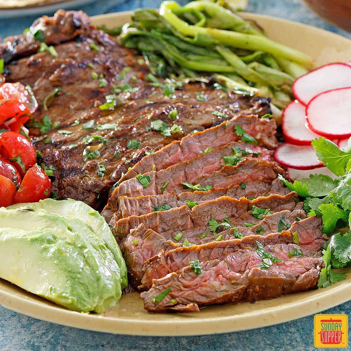 carne asada sliced on a plate with vegetables