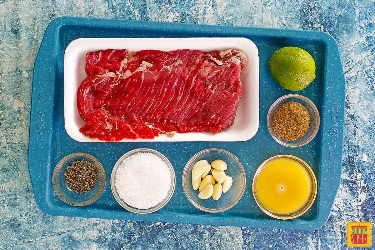 Steak with carne asada ingredients on a blue tray