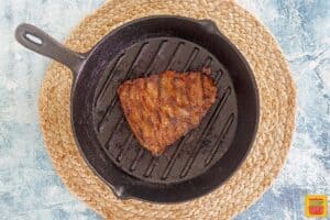 grilling steak for carne asada in a black pan