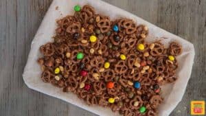 Peanut butter pretzel snack mix spread out on a parchment paper-lined baking sheet