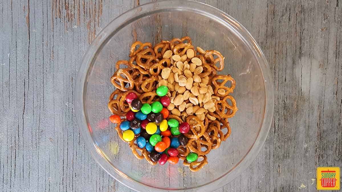 Peanuts, pretzels, and M&Ms in a glass bowl