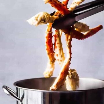 Pulling crab legs out of a stock pot with tongs