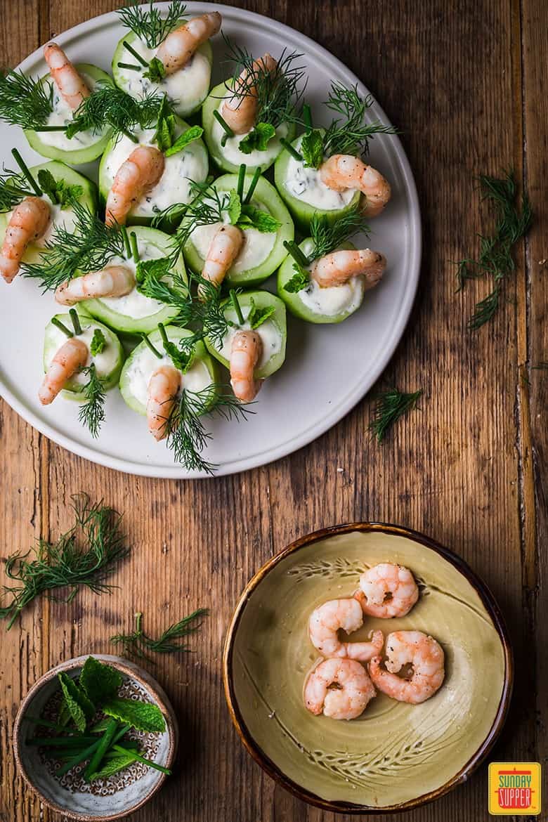 shrimp appetizers on a white plate with cooked shrimp in a bowl