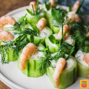 Cucumber canapes with shrimp on a white plate with fresh herb topping