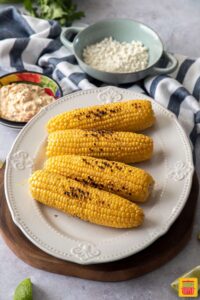 Grilled corn on a white platter for elotes Mexicanos