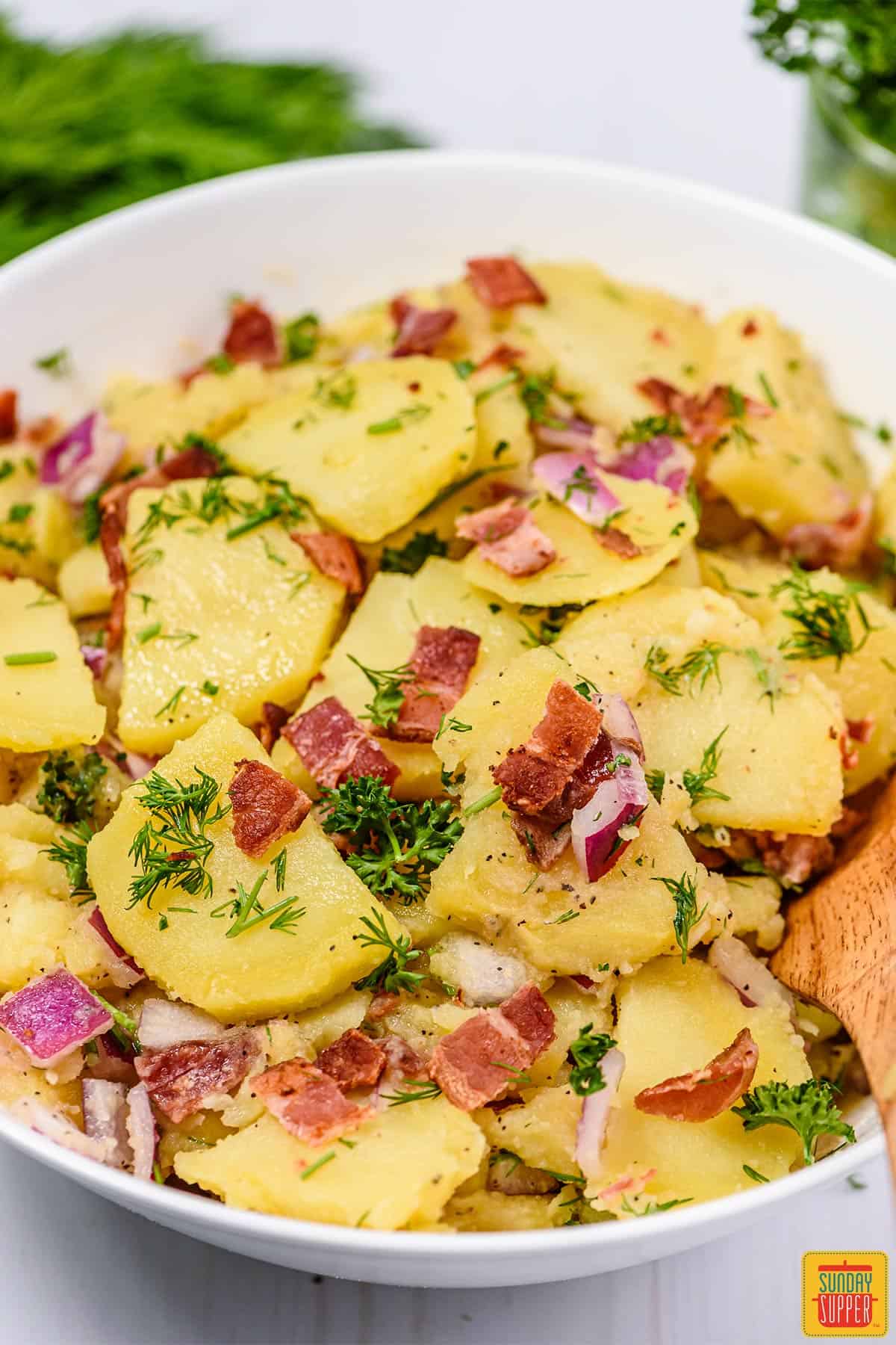 close up of german potato salad in a white bowl