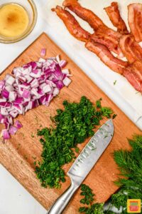 Chopped herbs and onions next to cooked bacon