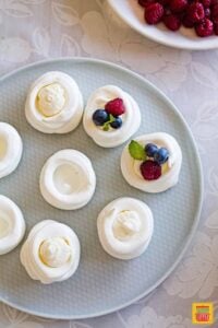 Filling piped into mini pavlovas on a light blue plate