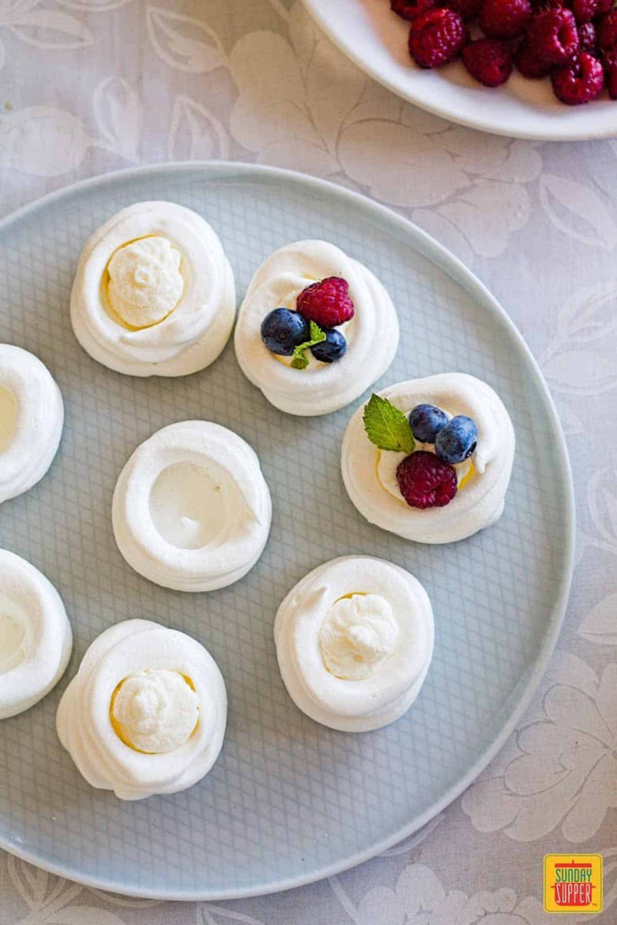 Filling piped into mini pavlovas on a light blue plate