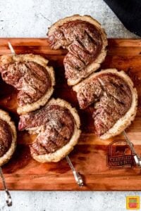 Four Picanha Steaks on skewers on a cutting board