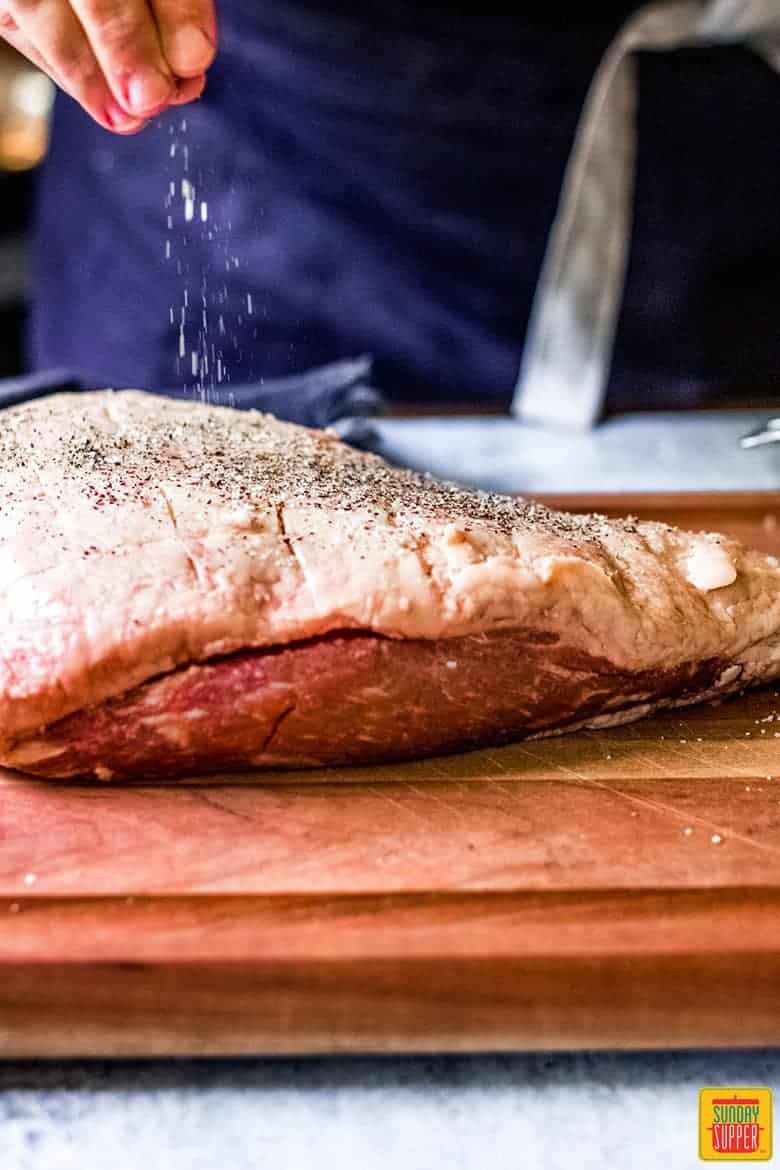 Seasoning Picanha steak before cutting to shape.