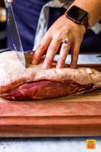 a woman scoring the fat cap of a Picanha