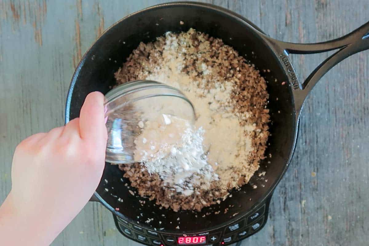 Adding flour to sausage gravy in skillet