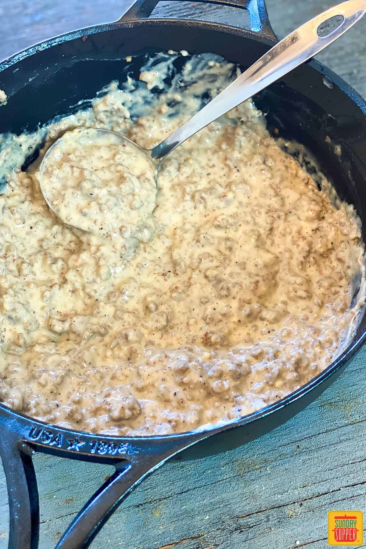 Sausage gravy in a skillet with a ladle
