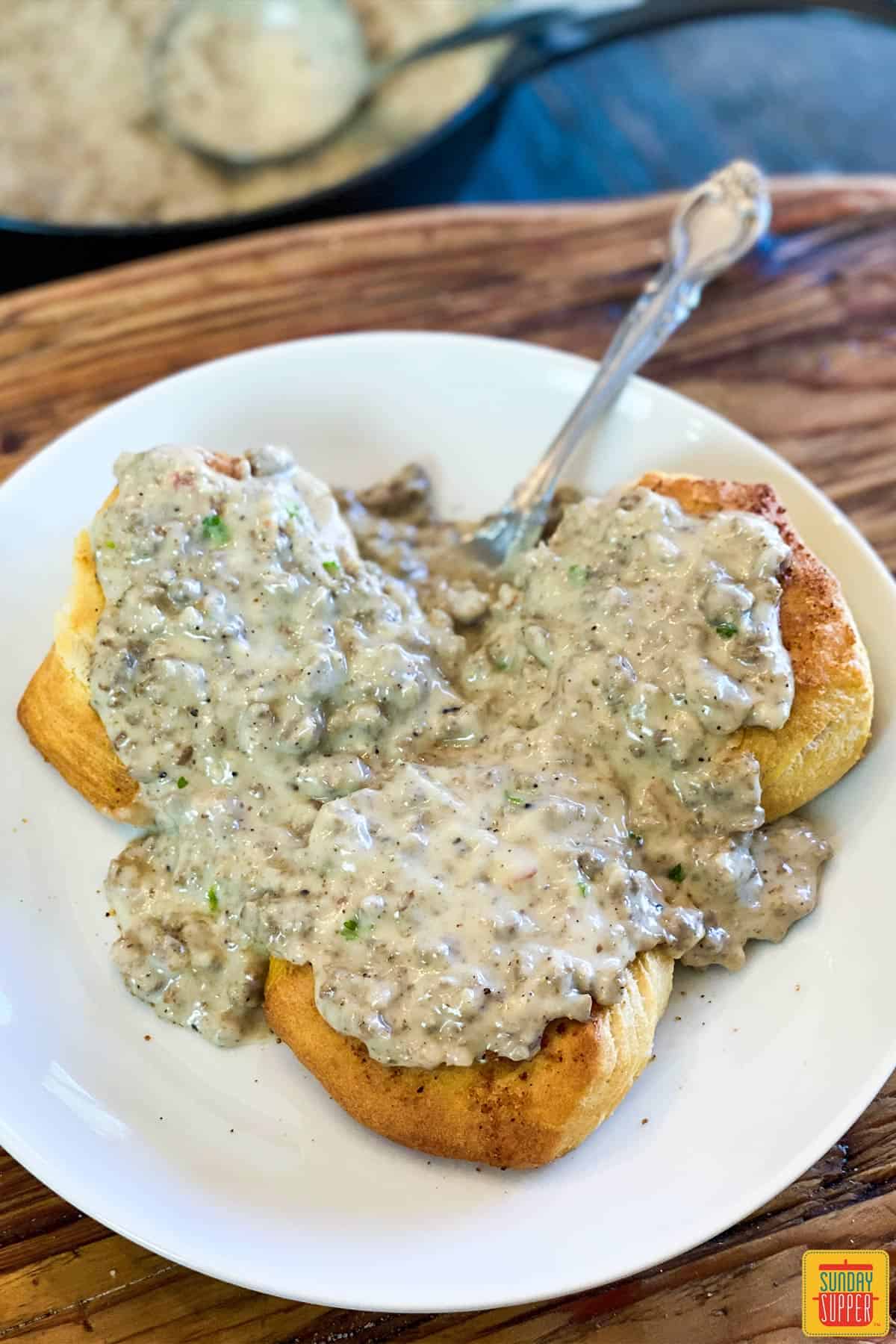 Close up of three sausage gravy biscuits on a white plate