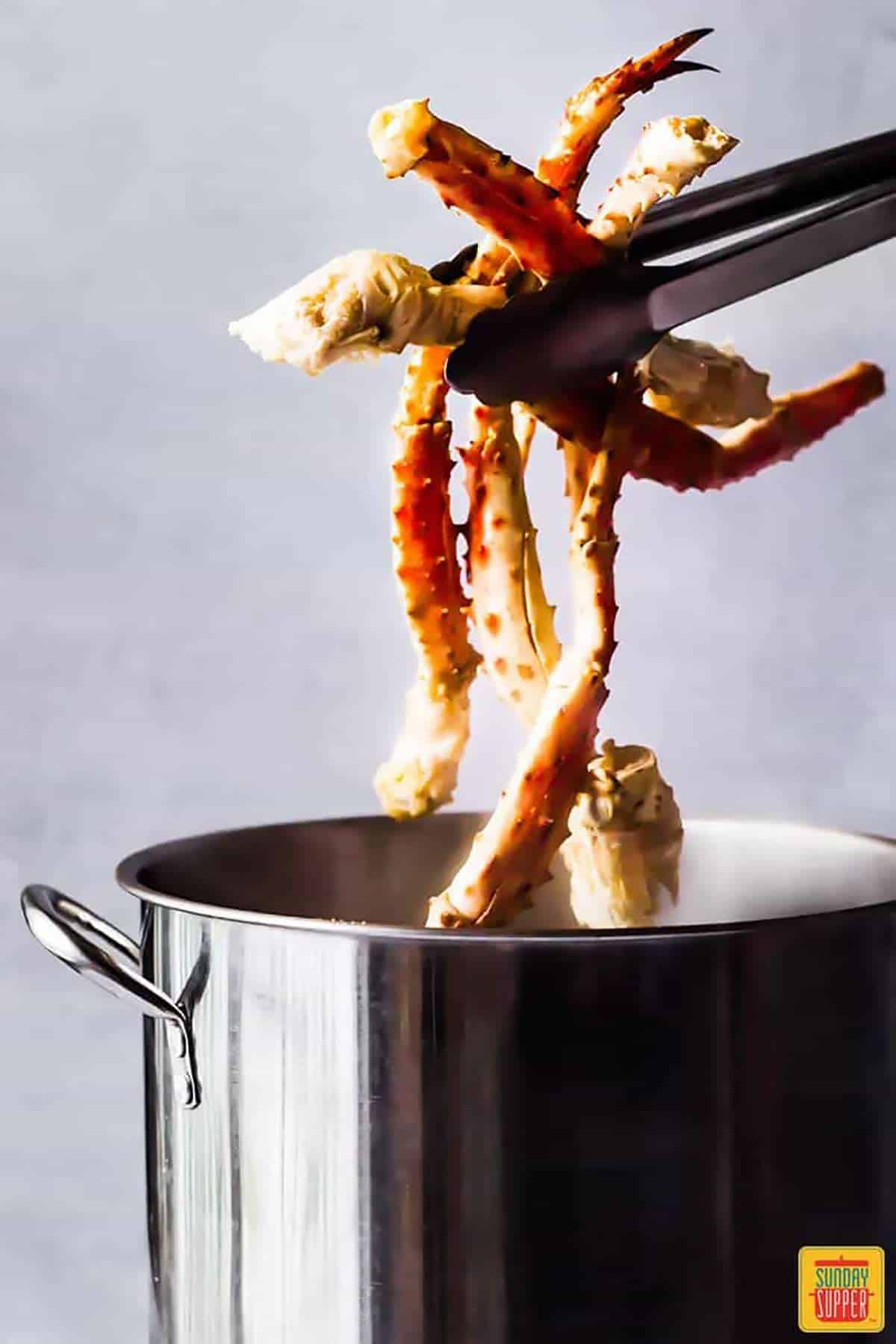 Pulling crab legs out of a stock pot with tongs