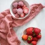 Frozen strawberries in a white bowl near a bowl of fresh strawberries: how to freeze strawberries