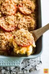 Ina Garten Mac and Cheese in casserole dish with wooden spoon lifting out a portion