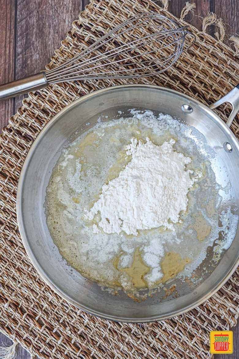 Mixing flour and butter in the pan to create the roux for slow cooker beef gravy