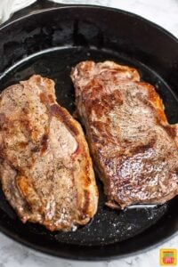 New york strip steaks searing in a skillet to make Steak diane