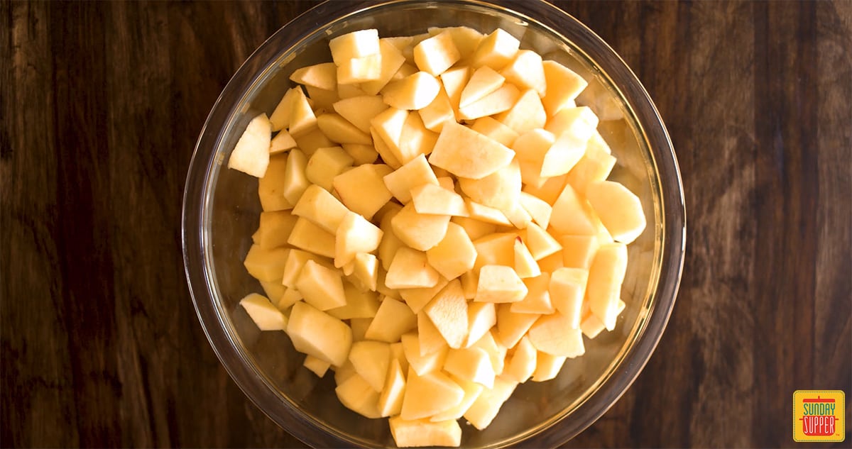 Apples diced in a bowl on a wooden surface