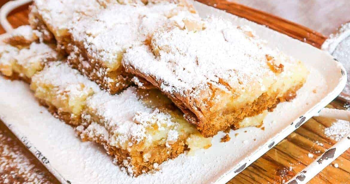 squares of ooey gooey butter cake on a rustic white serving platter