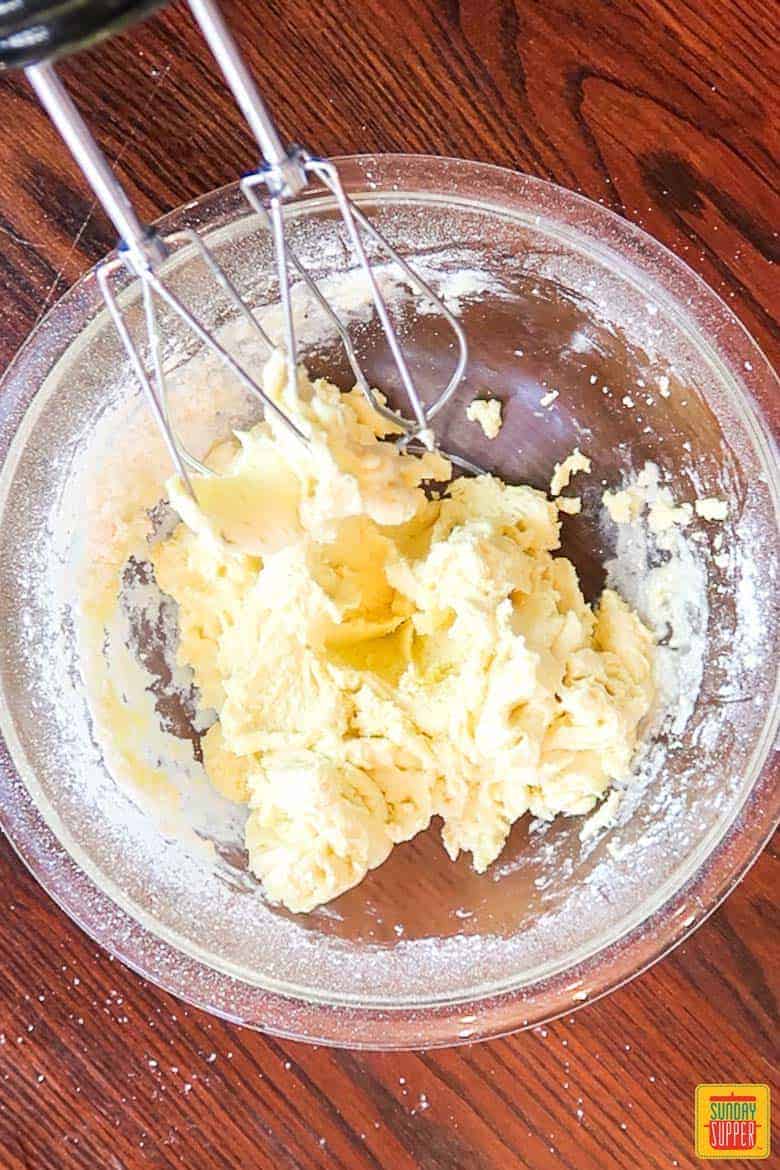 mixing ooey gooey butter cake batter in a bowl with electric mixer