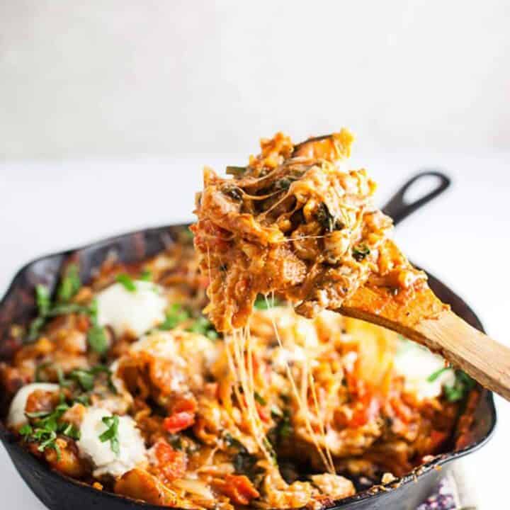 Wooden spoon with skillet lasagna over skillet