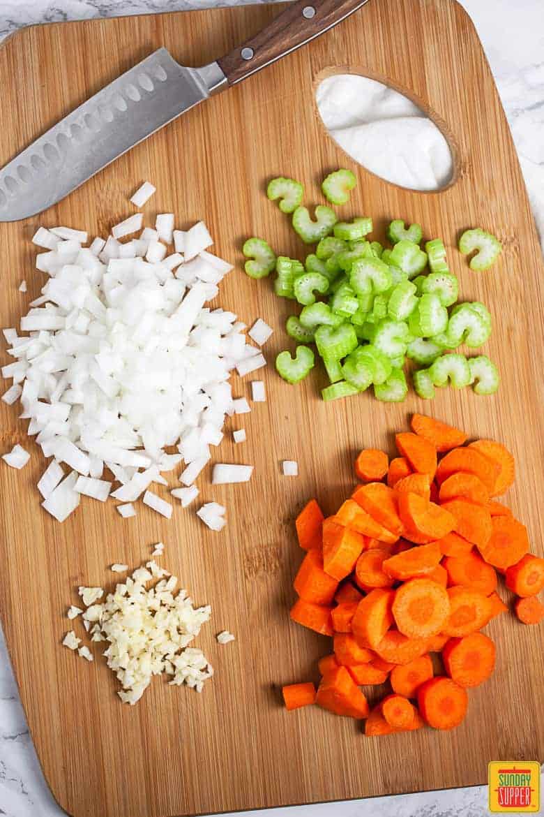 Minced Garlic, Onions, Celery, and Carrots On Cutting Board