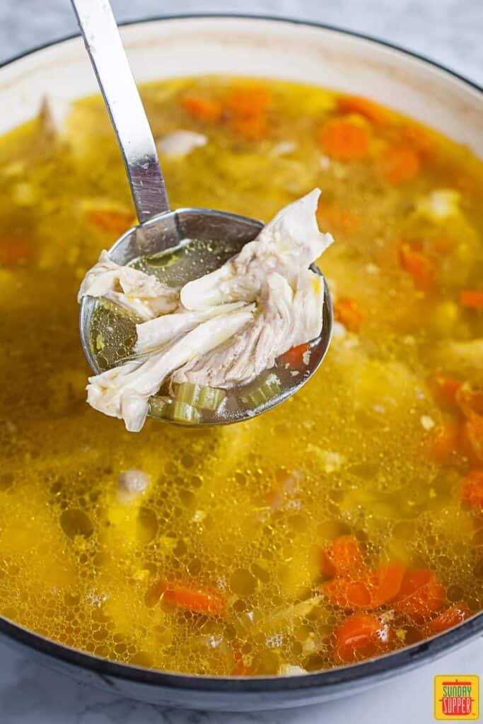 Scoop of Chicken Soup Simmering In Soup Pan