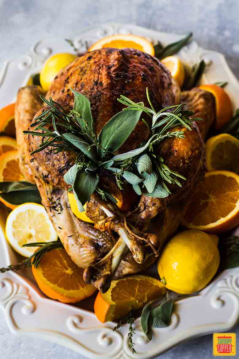 Best Thanksgiving Turkey Recipe on a decorative platter surrounded by citrus