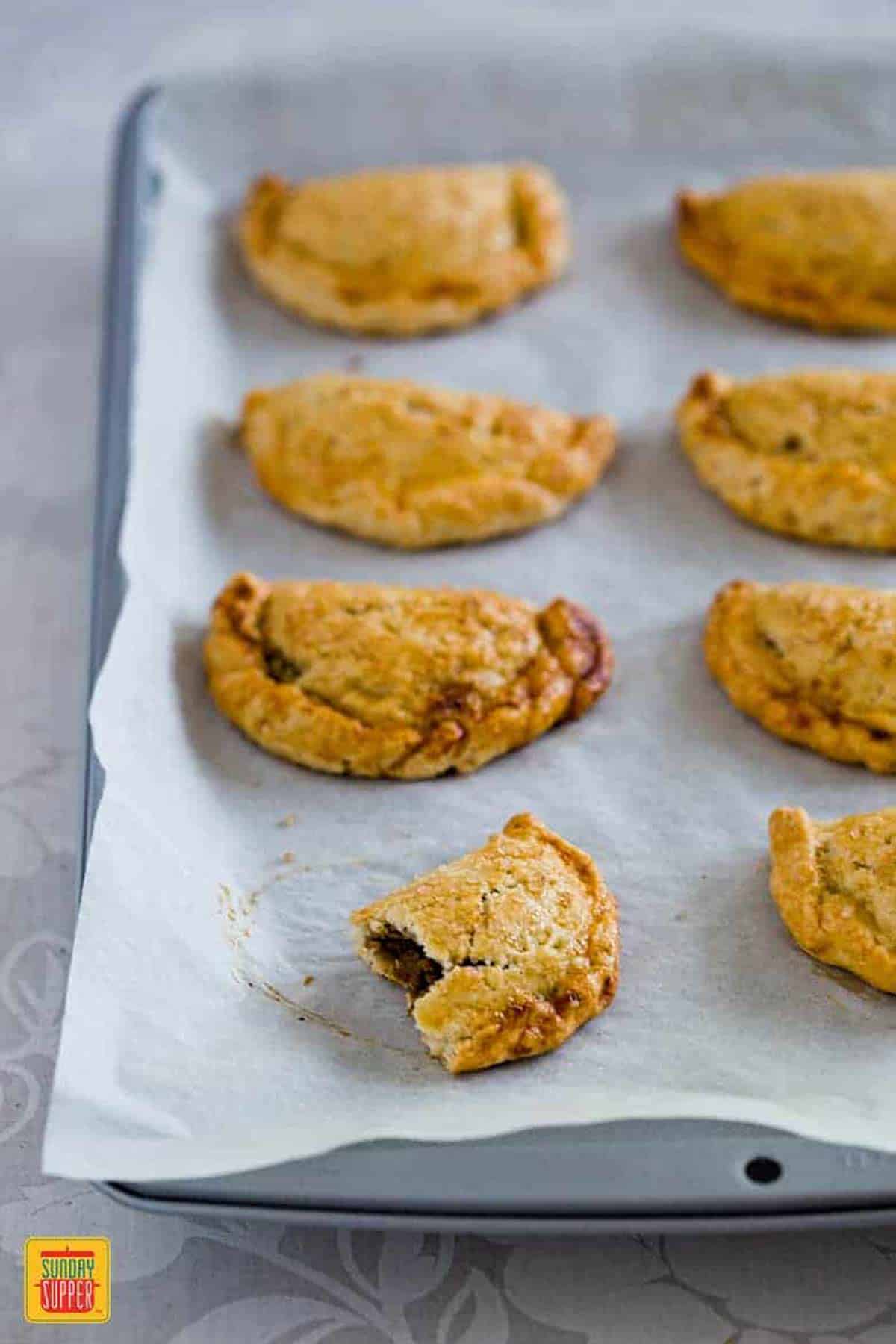 Baked Pumpkin empanadas in a tin on a sheet of parchment paper