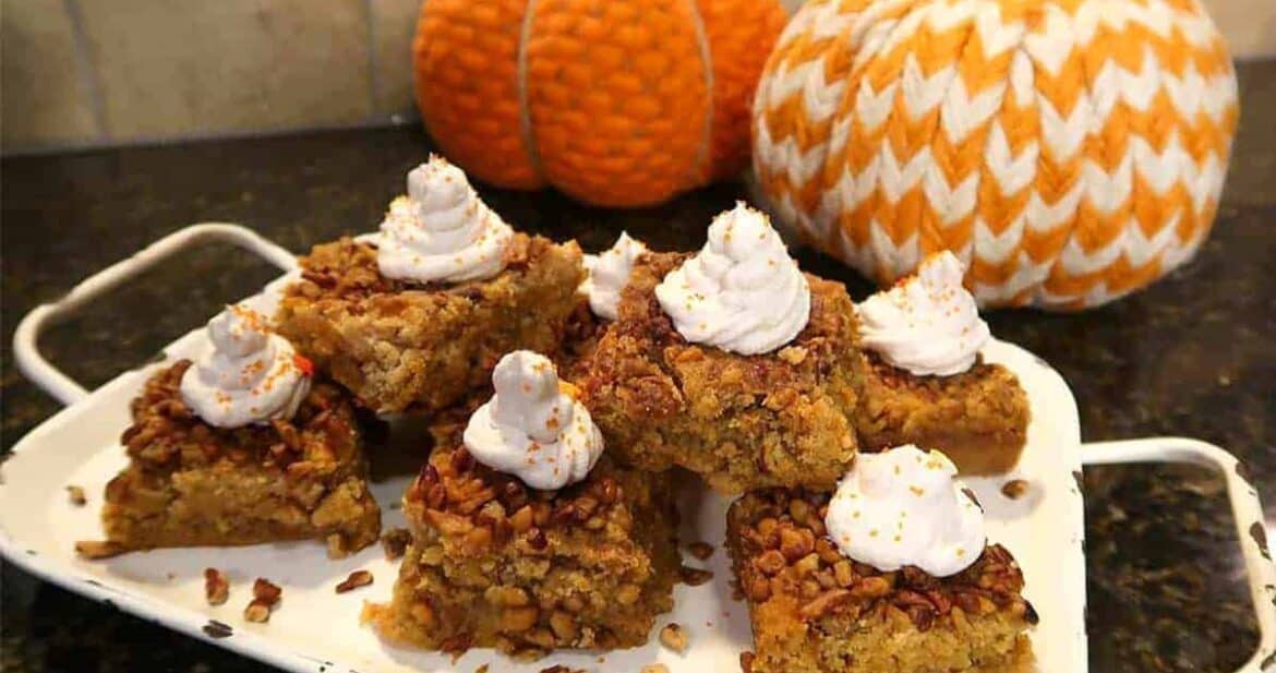 Pumpkin crunch cake bars on a white platter with fabric pumpkins in the background